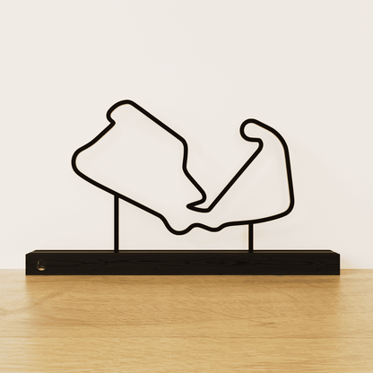 Minimalistisch Silverstone circuit silhouet van zwart staal op een matzwart eikenhouten voetstuk.