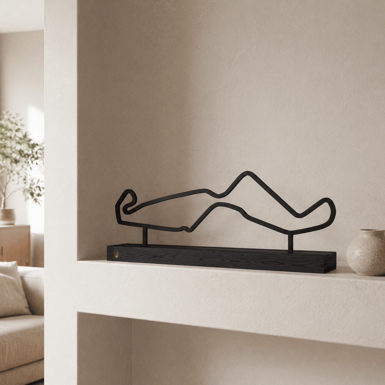Het stalen silhouet van het TT Circuit Assen op een zwart eikenhouten voet, gestyled in een wandnis.