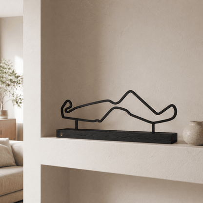 Het stalen silhouet van het TT Circuit Assen op een zwart eikenhouten voet, gestyled in een wandnis.